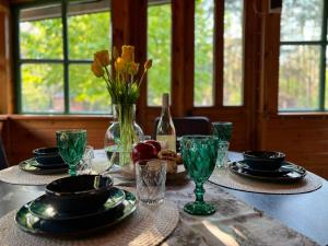 uma mesa com pratos e copos e um vaso de flores em Leśny Zakątek em Krajęczyn
