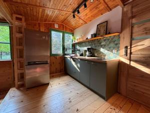 eine Küche mit einem Kühlschrank aus Edelstahl und Holzdecken in der Unterkunft Leśny Zakątek in Krajęczyn