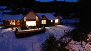 uma cabana de madeira na neve à noite em Villa Soñada - Encantadora Casa para 6 Personas em Esquel