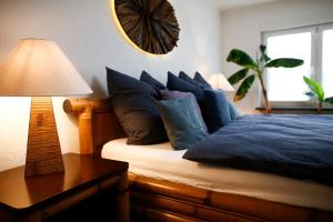 1 dormitorio con 1 cama con almohadas azules y lámpara en Schlossberg Apartments & Garten in der Natur & unweit vom "Thüringer Meer" en Unterwellenborn