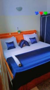 - un lit bleu et blanc avec des oreillers bleus dans l'établissement Résidences Hôtel Perle Bleue, à Cotonou