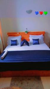 uma cama grande com almofadas azuis e brancas em Résidences Hôtel Perle Bleue em Cotonou