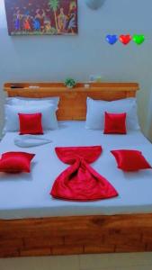 a bed with red pillows and a red dress on it at Résidences Hôtel Perle Bleue in Cotonou
