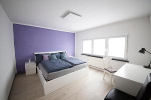 1 dormitorio con cama y pared púrpura en Schlossberg Apartments & Garten in der Natur & unweit vom "Thüringer Meer" en Unterwellenborn