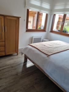 ein Schlafzimmer mit einem großen Bett und zwei Fenstern in der Unterkunft Gîte chez Alice in Mollkirch