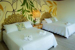 a room with two beds with white towels on them at Ecohotel Yachay Tayrona in El Zaino