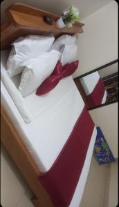 Una cama con almohadas rojas y blancas y una pajarita. en Résidences Hôtel Perle Bleue, en Cotonou