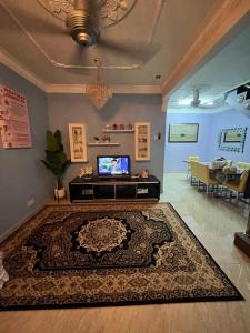 a living room with a television and a rug at Iwan Ila Homestay in Batang Kali