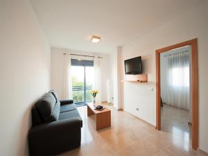 a living room with a couch and a television at Apartamentos Varadero On the beach in Cala del Moral