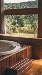 La salle de bains est pourvue d'une baignoire et d'une fenêtre. dans l'établissement Estalagem Tronador, à Camanducaia