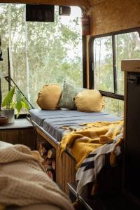 a room with a bed and pillows in a train at Bus & Hot Tub Secluded Eco Forest Retreat in Bagdad