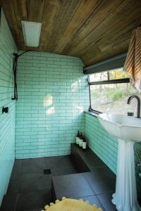 a bathroom with a sink in a green tiled wall at Bus & Hot Tub Secluded Eco Forest Retreat in Bagdad
