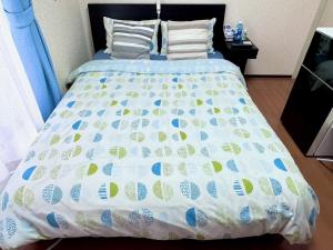 a bed with a blue and white comforter on it at Grandeur Imagawa - Vacation STAY 11149 in Urayasu