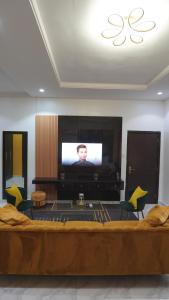 uma sala de estar com uma televisão e um sofá e cadeiras em SHORTLETMART Apartments em Lekki