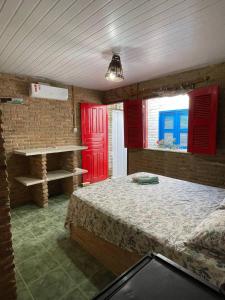 a bedroom with a bed and red doors and windows at Pousada sol nascente in Beberibe