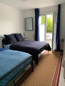 a bedroom with two beds and a sliding glass door at Chambres Senonches centre-ville in Senonches
