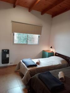 1 dormitorio con 2 camas y ventana en Complejo Quiya - Casa El Algarrobo en Alta Gracia