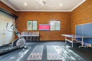 a room with a gym with a table and a tv at Karinya - Luxurious soul sanctuary by the surf. in Rye