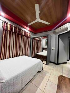 a bedroom with a white bed and a ceiling fan at Casa primavera Quepos in Quepos