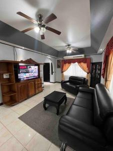 ein Wohnzimmer mit Sofas und einem Flachbild-TV in der Unterkunft Casa primavera Quepos in Quepos