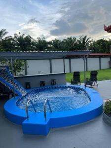 a large blue pool with a slide and chairs at Casa primavera Quepos in Quepos