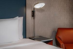 a bedroom with a bed and a lamp and a chair at Courtyard Boston Marlborough in Marlborough