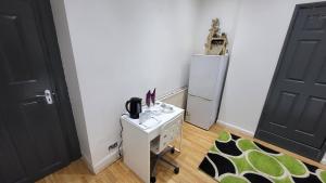 a room with a refrigerator and a table and a door at Oleon en-suite Rooms - Ilford, London in Ilford