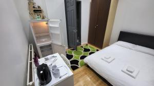 Habitación pequeña con cama blanca y escritorio. en Oleon en-suite Rooms - Ilford, London, en Ilford