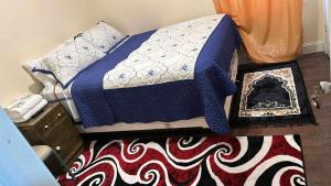 1 cama con manta azul y blanca y alfombra en Room F Divine Villa and Resorts 5mins to EWR Airport and 4mins to Penn Station Newark, 20Mins to New York en Newark