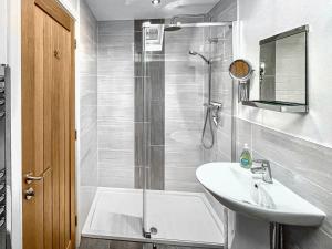 baño blanco con ducha y lavamanos en 8 Old School Mews, en Shanklin