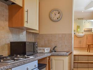 a kitchen with a clock on the wall at Waterside Cottage in Saltash