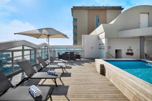 a deck with chairs and a swimming pool on a building at Protea Hotel by Marriott Durban Umhlanga in Durban