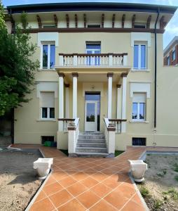 une grande maison jaune avec des escaliers et un balcon. dans l'établissement Domus 44 Rooms, à Vérone