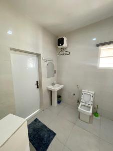 a white bathroom with a toilet and a sink at Cozy And Serene Studio Apartment in Abuja