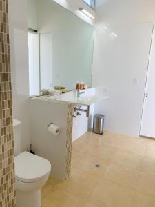 a white bathroom with a toilet and a sink at Lush Pastures in Bald Hills