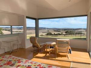 Zimmer mit einem Tisch und Stühlen sowie einem großen Fenster in der Unterkunft Lush Pastures in Bald Hills