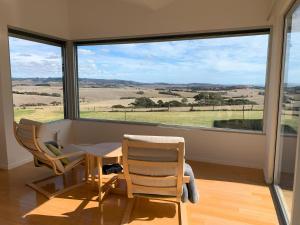 a room with a table and two chairs and a large window at Lush Pastures in Bald Hills