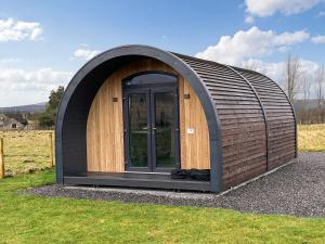 a circular shed with a door in the grass at Bombie Glamping Pod in Cromdale