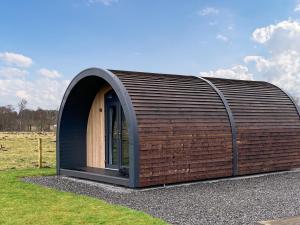 a small building with a wooden door in a field at Bombie Glamping Pod in Cromdale