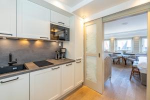 a kitchen with white cabinets and a dining room at Kampenkliff ehemals Walter´s Hof in Kampen