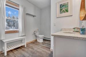 a white bathroom with a toilet and a window at Ocean View Duplex with Walk to Beach in Owls Head