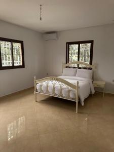 een wit bed in een witte kamer met ramen bij La casa d’ourika in Ourika