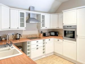 Brandy Cottage - Ukc6855 في Millton of Clova: مطبخ مع دواليب بيضاء ومغسلة