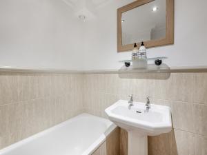 a bathroom with a sink and a mirror and a tub at The School Room in Dymock