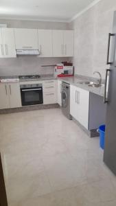 eine Küche mit weißen Schränken, einer Spüle und einem Geschirrspüler in der Unterkunft Apartment in Nador in Nador