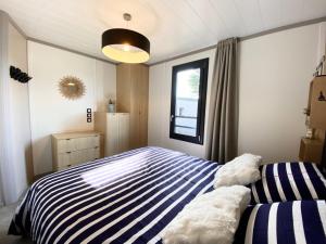 - une chambre avec un lit rayé et une fenêtre dans l'établissement Chalet cozy à Jullouville - 4 pers, piscine chauffée, proche plage et commerces - FR-1-361-538, à Jullouville 26 autres photos