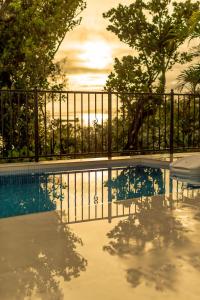 une piscine en face d'une clôture avec un coucher de soleil dans l'établissement -Villa Rikyu- 離宮, à Île Miyako