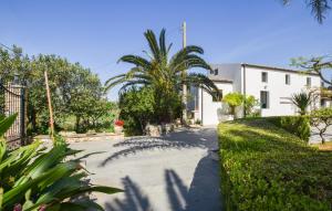 una calle con palmeras y un edificio blanco en Beautiful Home In Chiaramonte Gulfi With Wifi en Chiaramonte Gulfi