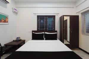 um quarto com uma cama grande e lençóis brancos e pretos em OYO ARN RESIDENCY em Chennai