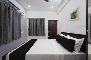 um quarto com uma cama grande e almofadas pretas e brancas em OYO ARN RESIDENCY em Chennai